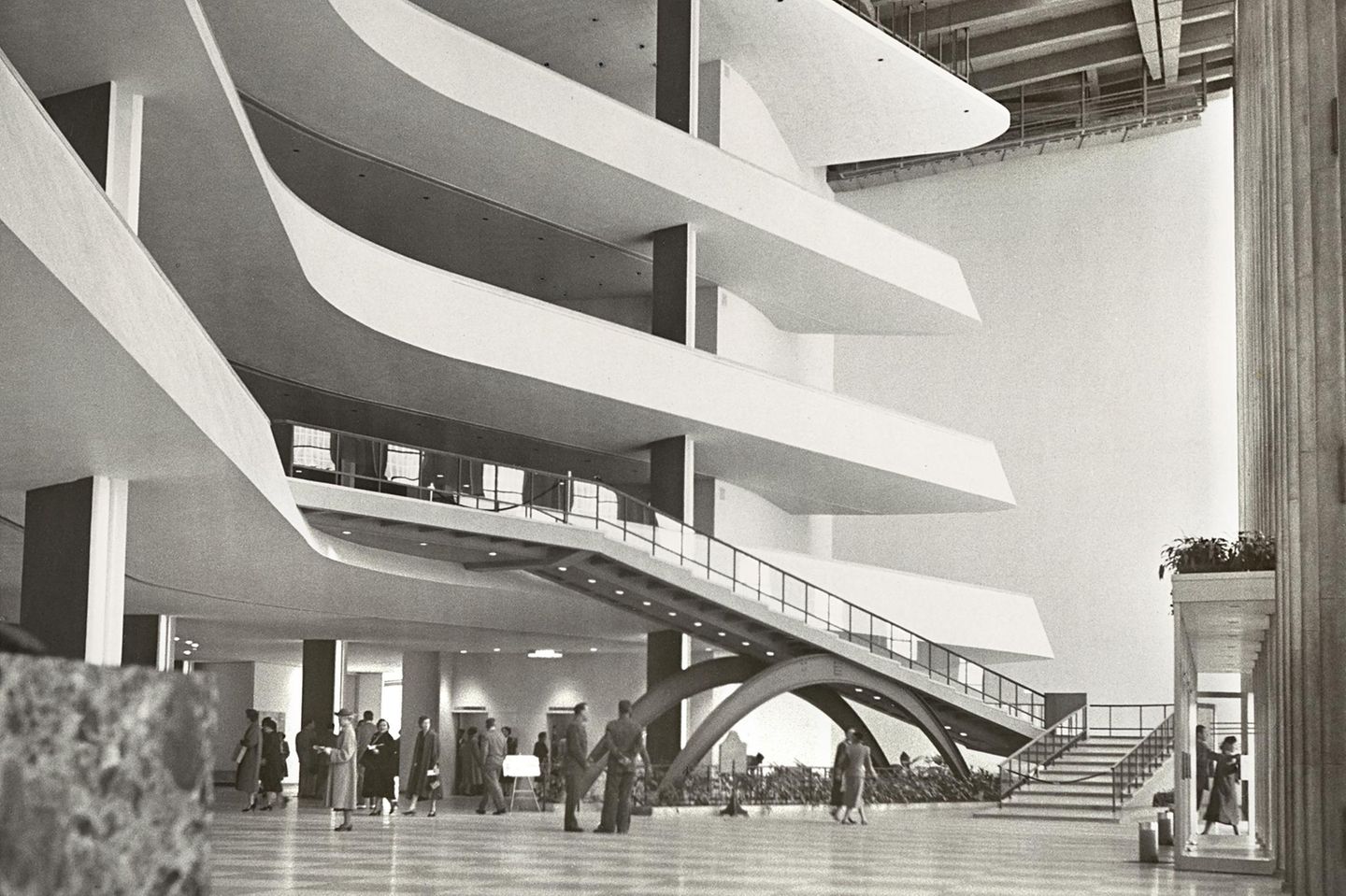Hohe Eingangshalle mit mehreren, langen und geschwungenen Balkonen und Balkendecke; sw-Foto, 1957