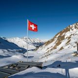 Schweizer Flagge und Berghütte Keschhütte vor Berglandschaft im Winter