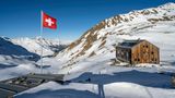 Schweizer Flagge und Berghütte Keschhütte vor Berglandschaft im Winter