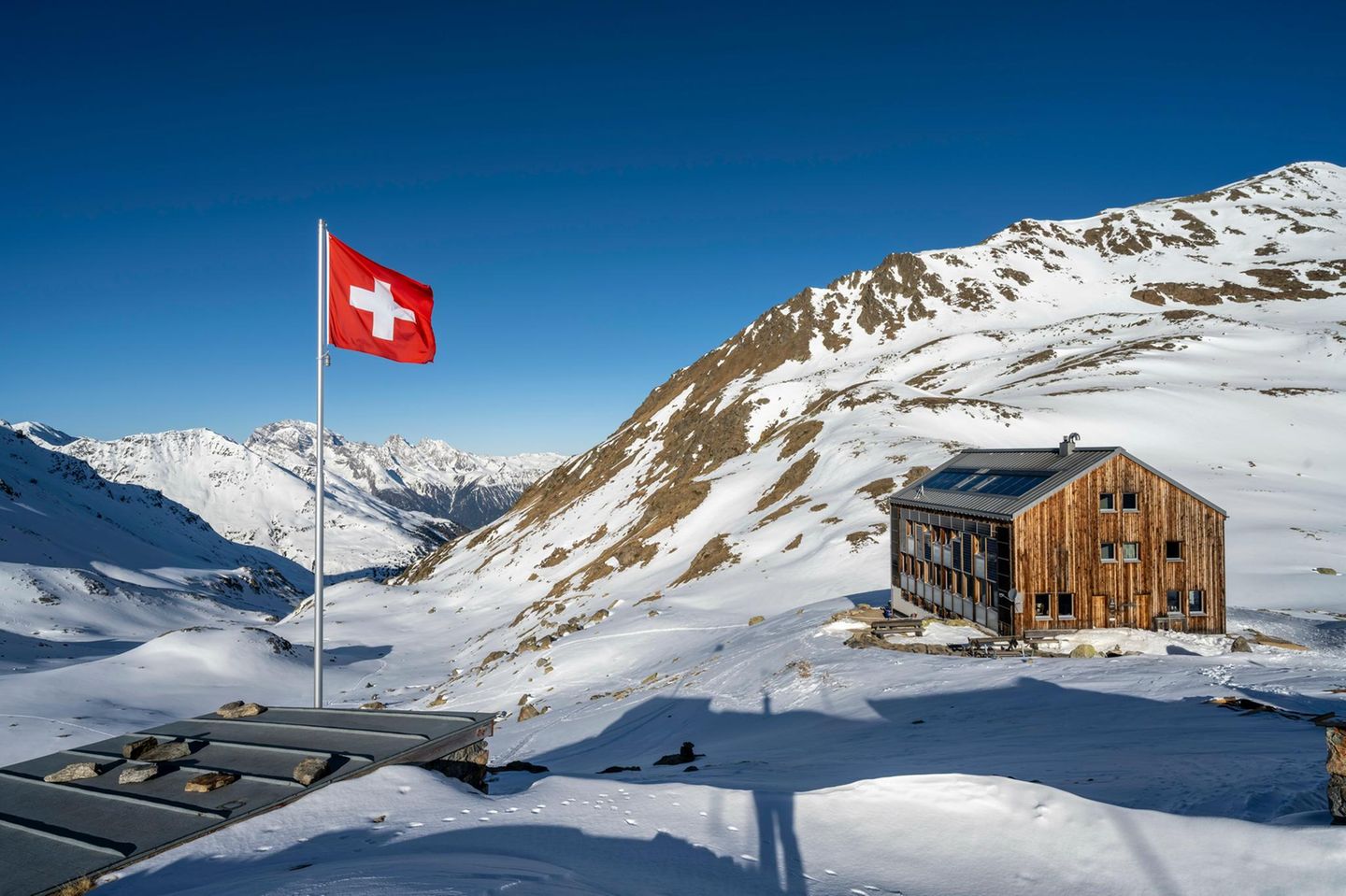 Schweizer Flagge und Berghütte Keschhütte vor Berglandschaft im Winter