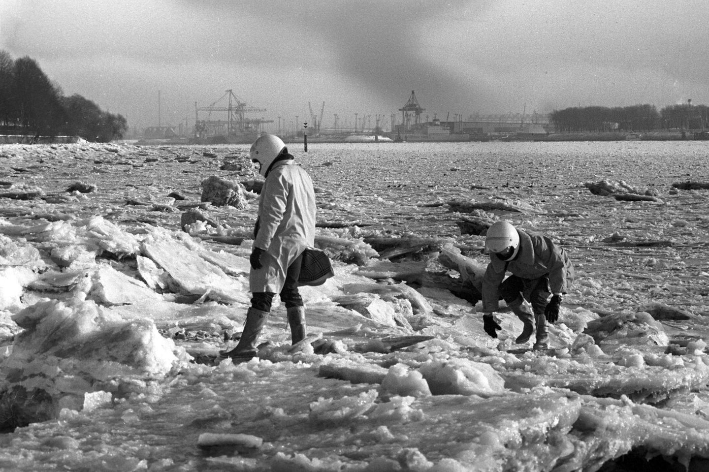 Schneekatastrophe zwei Männer mit Motorradhelmen auf Eisschollen