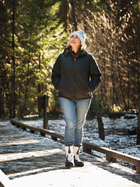 Eine Frau mit weisser Mütze wandert im Winter auch den Wald