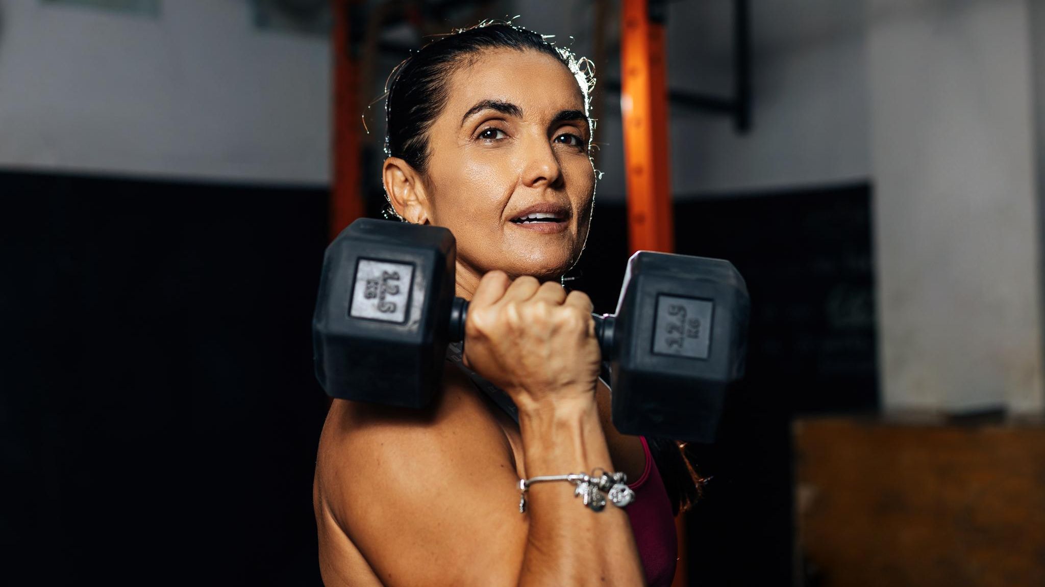Eine Frau mittleren Alters hebt eine Hantel im Fitnessstudio hoch