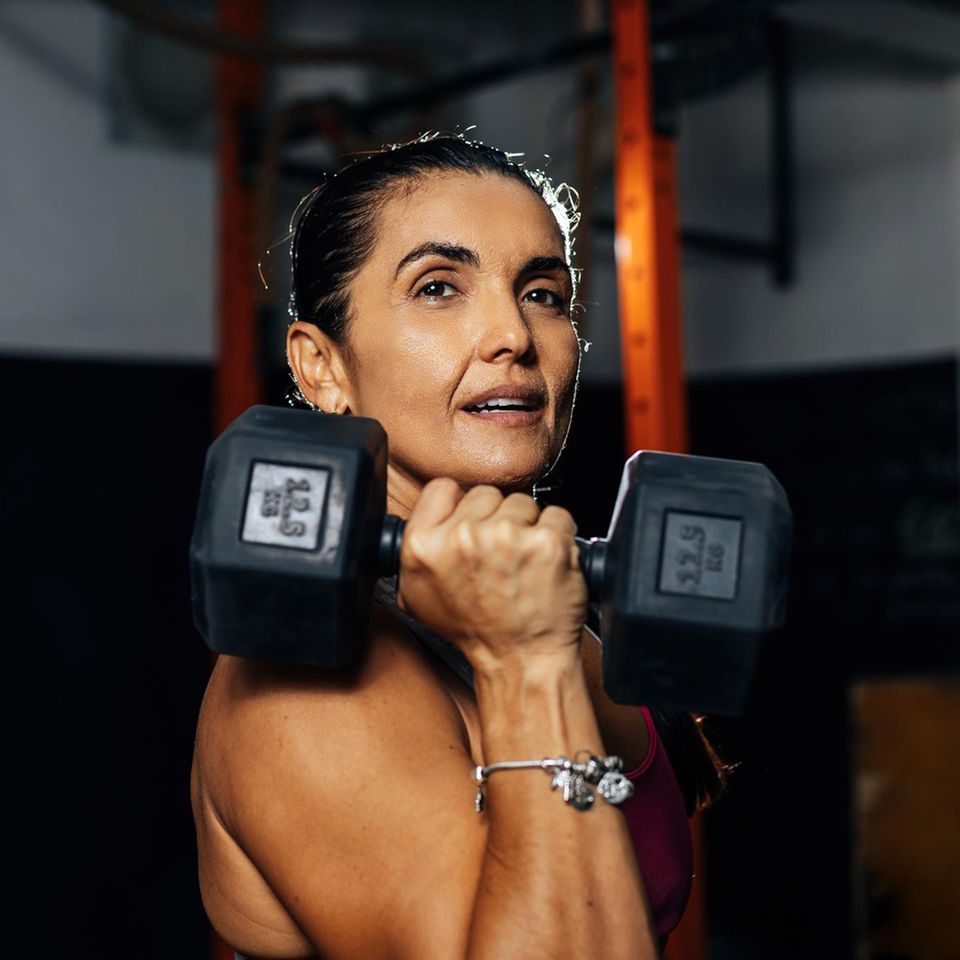 Eine Frau mittleren Alters hebt eine Hantel im Fitnessstudio hoch