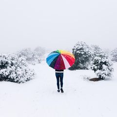Mann mit Regenschirm im Schnee bei Schneefall