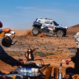 Zuschauer bereiten in Saudi-Arabien auf traditionelle Weise Tee zu, während im Hintergrund ein Rennwagen der Rallye Dakar Staub aufwirbelt. Der Wettbewerb hat eine lange Geschichte, hieß ursprünglich "Ralley Paris-Dakar", gastierte auch schon in Südamerika und wird inzwischen von Saudi-Arabien ausgerichtet. Wegen vieler Todesfälle, hoher Kosten und ökologischer Folgen steht die Veranstaltung seit Jahren in der Kritik. 
