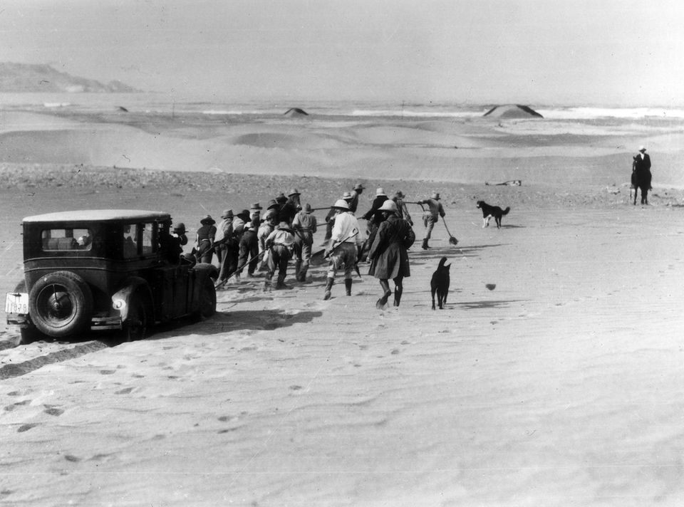 Das Auto von Claerenore Stinnes wird von Menschen aus dem Sand gezogen