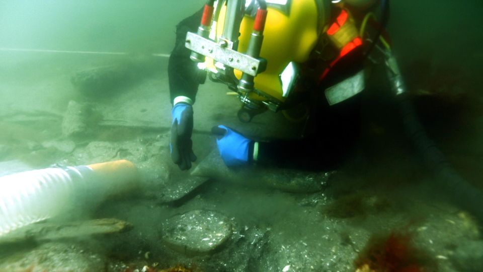 Taucher mit Unterwasserstaubsauger am Meeresgrund