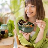 Junge fröhliche Frau isst eine vegetarische Bowl