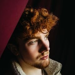 Junger Mann mit roten Locken schaut nachdenklich