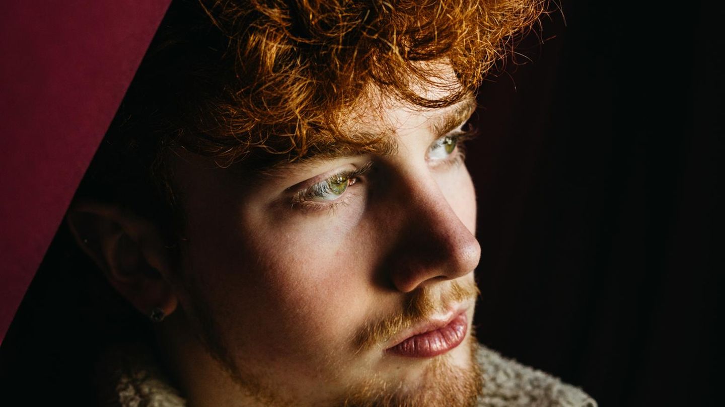 Junger Mann mit roten Locken schaut nachdenklich