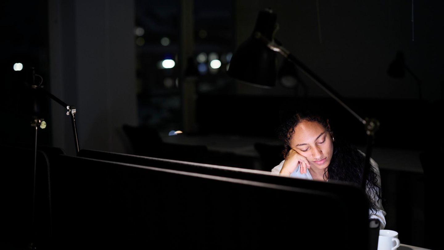 Eine Frau sitzt noch spätnachts vor einem Computerbildschirm