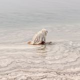 Am Ufer des Toten Meeres, in Jordanien, hockt eine Frau im flachen Wasser und tastet nach Salzsteinen. Beinahe entrückt erscheint die Szene und sie ist Teil einer Jahrtausende alten Tradition: Den Mineralen des hypersalinen Sees wird eine reinigende und heilende Wirkung zugeschrieben. Das Salz soll die Haut beruhigen, die Muskeln entspannen, kleine Wunden versiegeln. In Jordanien gehören Rituale der Pflege und Reinigung für viele zum Alltag, wobei sie heute auch in die Wellnessindustrie und den Tourismus reichen.   Die Aufnahme ist Teil des internationalen "Walk of Water"–Fotowettbewerbs von UNESCO und Onewater. Die ausgezeichneten Bildgeschichten zeigen, wie eng Wasser mit Identität und Kultur verwoben ist – von rituellen Gesten bis zum alltäglichen Überleben.