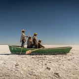 Auf der schier endlosen Salzfläche des ausgetrockneten Poopó-Sees versammeln sich Florencio, Pablo, Cipriana und Félix Mauricio in einem Boot. Ein Relikt aus Zeiten, in denen hier noch Fische statt Staub ihr Dasein bestimmten. Die Qotzuñi haben ihre traditionelle Existenz verloren: Mit dem Klimawandel, dem Wasserentzug für Landwirtschaft und Bergbau verschwand eines der größten Binnengewässer Boliviens fast vollständig. Heute widmet sich die Gemeinschaft dem Kunsthandwerk, um Erinnerung und Identität zu bewahren. Die Inszenierung auf der dürren Ebene ist eine Art Denkmal: für eine Kultur, die sich neu erfinden musste, und für ein Ökosystem, das nicht zurückkehren wird.