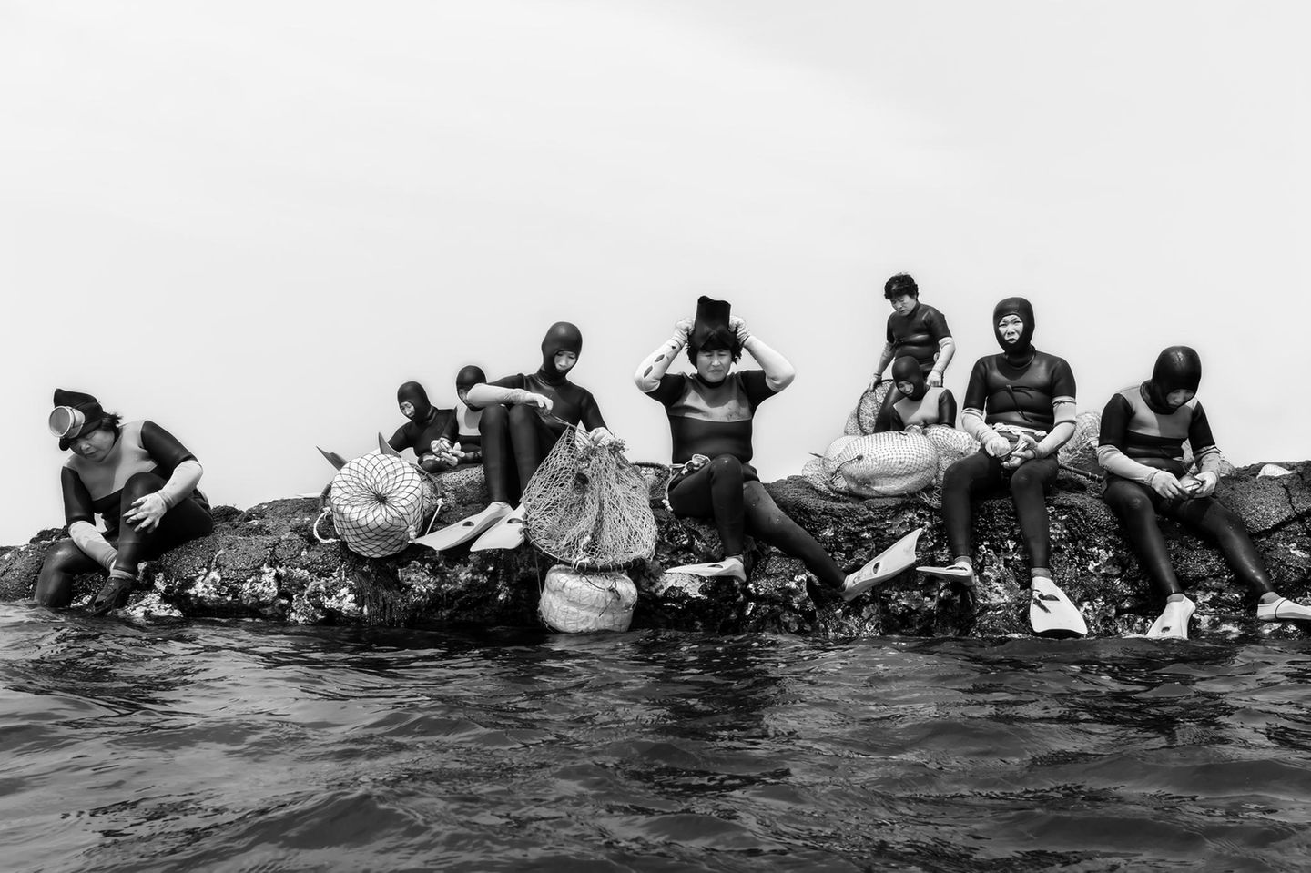In der südkoreanischen Provinz Jeju arbeiten die Haenyeo: Taucherinnen, die sich ohne Sauerstoffflaschen in die blaue Tiefe begeben. Der Moment vor dem Abtauchen wirkt ruhig: Die Frauen sitzen auf dem Fels, prüfen Netze, Flossen und Masken, sammeln Kraft. Doch ihr Handwerk verlangt Härte und Präzision. Unter Wasser halten sie minutenlang die Luft an, navigieren durch Strömungen, lesen das Meer und ernten Seeohren, Seeigel oder Algen. Das charakteristische Pfeifen beim Auftauchen, "Sumbisori" genannt, ist zugleich Atemtechnik und Lebensversicherung. Seit Jahrhunderten wird das Wissen weitergegeben; heute ist es bedroht, durch Überfischung, den Klimawandel und das zunehmend hohe Alter vieler Taucherinnen. In diesem Porträt sammelt sie sich, die ganze Konzentration einer Kultur, die vom Rhythmus des Ozeans lebt.