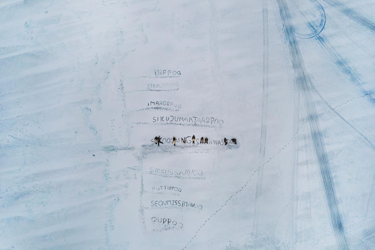 In Uummannaq, einer Siedlung im Nordwesten Grönlands, ritzen Kinder Worte ins Meereis. Die Begriffe stammen aus dem Kalaallisut, dem westgrönländischen Dialekt, der für seine Fähigkeit bekannt ist, komplexe Veränderungen in langen zusammengesetzten Wörtern zu fassen. Während das Eis früher monatelang als sichere Verkehrsfläche galt, wird es heute dünner, poröser, unberechenbarer. Die Kinder verwenden Sprache, um das Unfassbare zu vermessen: neue Begriffe für neues Wissen, neue Risiken, neue Gefühle. In diesem Bild werden das Schmelzen und die Unsicherheit sichtbar. Nicht durch Daten oder Karten. Dafür aber durch eine junge Generation, die versucht, einer verändernden Welt Bedeutung zu geben.