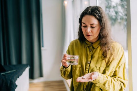 Eine Frau hält einige Tabletten in der Hand