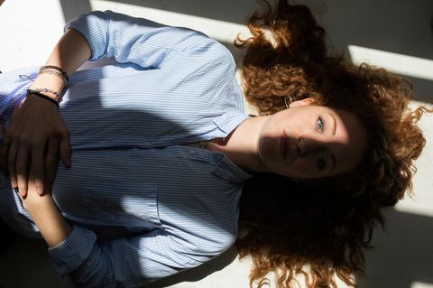 Eine Frau liegt entspannt auf dem Rücken. Sonne fällt durch ein Fenster auf ihr Gesicht