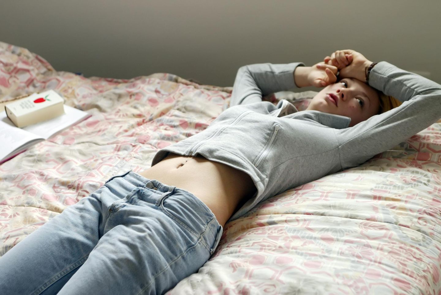 Junges dünnes Mädchen liegt auf dem Bett und starrt an die Decke