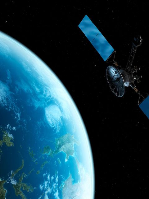 Computermontage von einem Satelliten der über der Erde im All schwebt