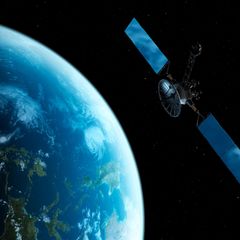 Computermontage von einem Satelliten der über der Erde im All schwebt