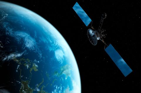 Computermontage von einem Satelliten der über der Erde im All schwebt