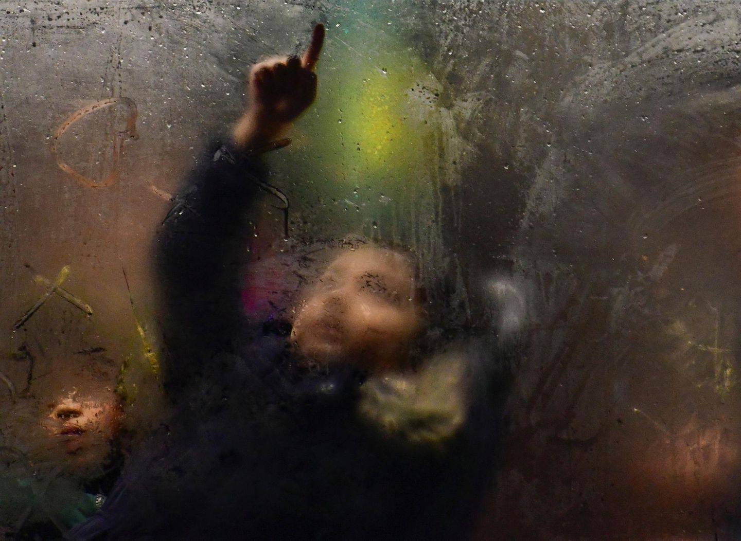 Kind im Bus zeichnet mit dem Finger auf beschlagene Scheibe