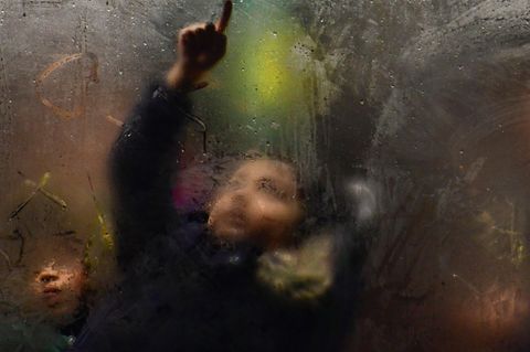 Kind im Bus zeichnet mit dem Finger auf beschlagene Scheibe