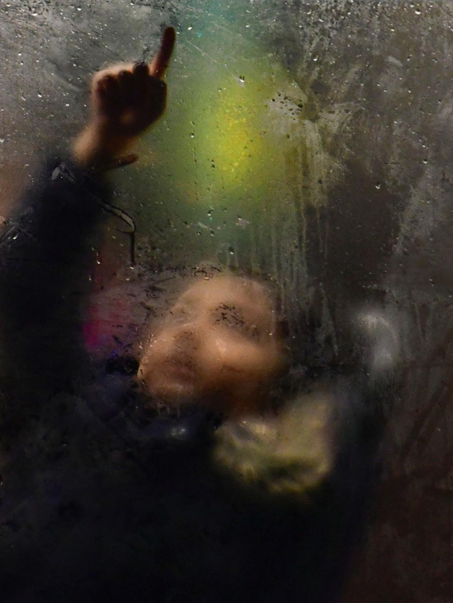 Kind im Bus zeichnet mit dem Finger auf beschlagene Scheibe