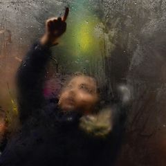 Kind im Bus zeichnet mit dem Finger auf beschlagene Scheibe