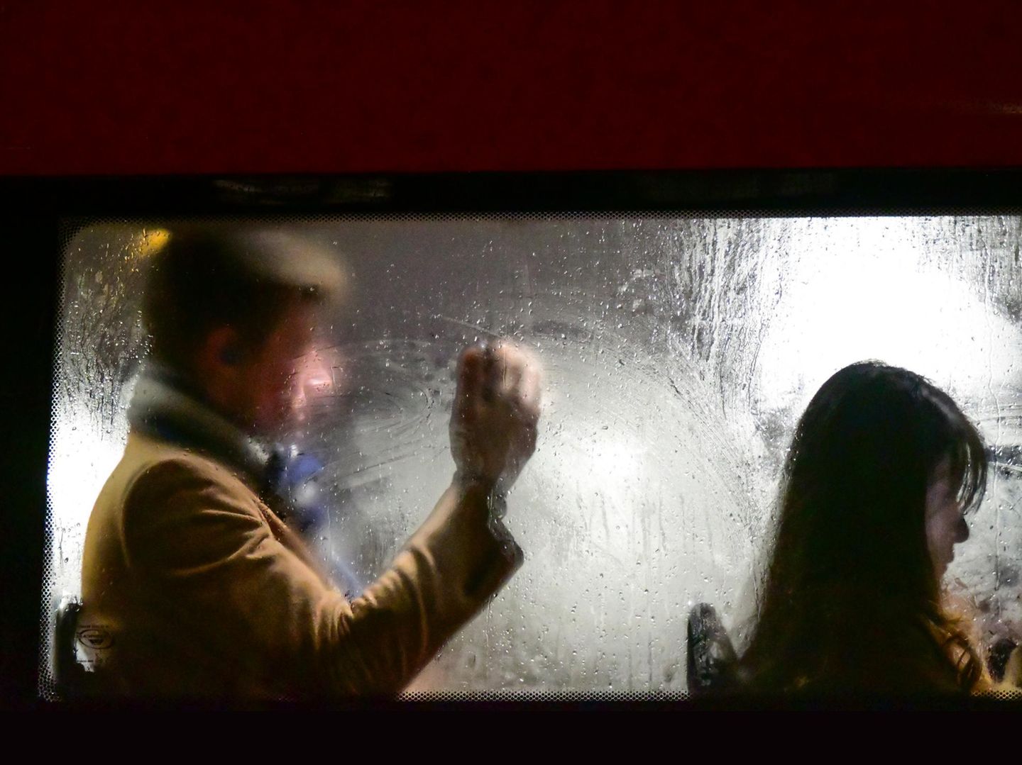 Mann sitzt hinter Frau im Bus