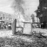 Ein brennender Kiosk liegt auf einer Straße, umgeben von Demonstranten