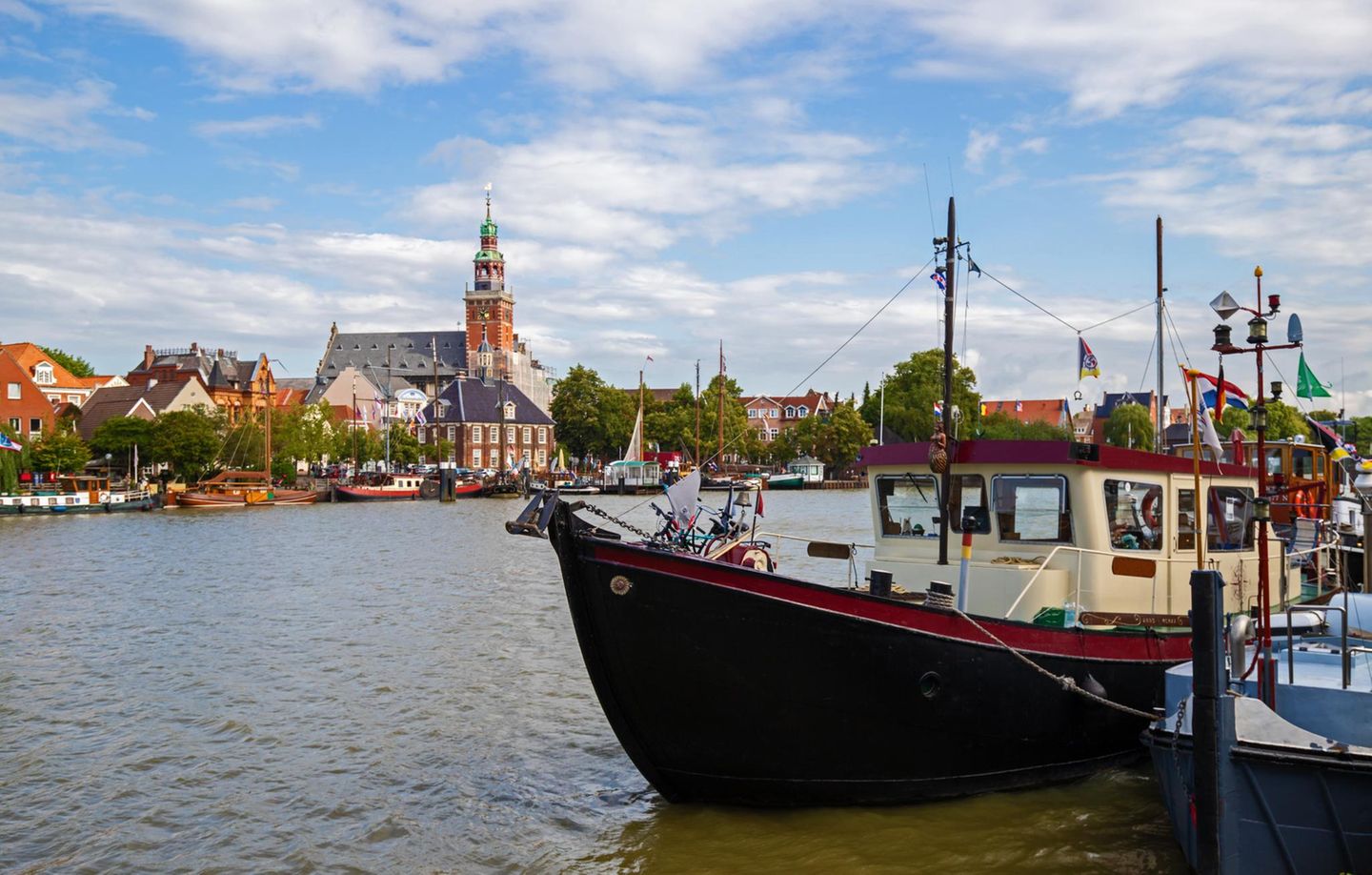 Der Stadthafen von Leer in Ostfriesland mit Schiffen und Blick auf das Rathaus.