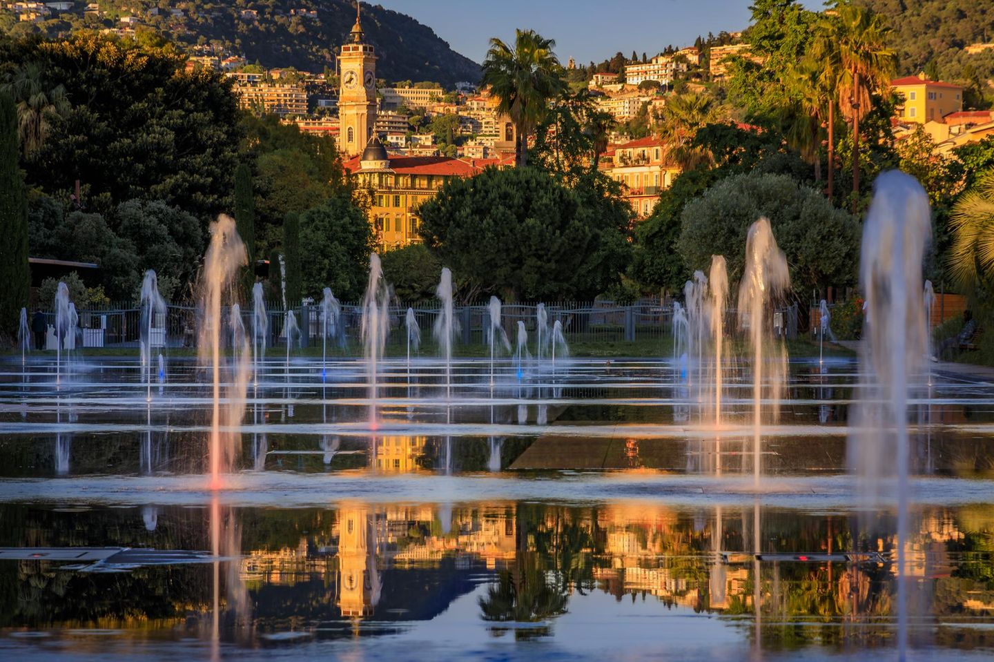 Durchatmen, abkühlen, schlendern: Die Promenade du Paillon zieht sich wie ein grünes Band vom Théâtre National de Nice und dem Museum für Moderne Kunst bis hinunter zum Meer. Auf rund zwölf Hektar wechseln sich Rasenflächen, Blumenbeete, Alleen, Spielplätze und Sitzbereiche ab. Herzstück der grünen Lunge Nizzas ist der Miroir d’Eau ("Wasserspiegel") am Place Masséna: eine weitläufige Wasserfläche mit zahlreichen Bodendüsen, die in Intervallen Fontänen und feine Nebelwolken in die Höhe schießen lassen. Besonders an heißen Sommertagen tobt hier das Leben: Kinder jagen kreischend durch die Wasserstrahlen, Erwachsene genießen den kühlenden Sprühnebel. Bei Windstille macht der Platz seinem Namen alle Ehre – dann spiegelt sich die Skyline der Stadt auf dem Wasser.