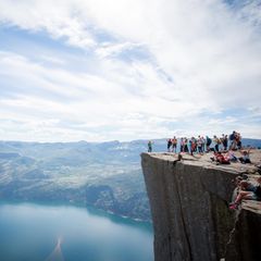 Felsplateau Preikestolen mit Menschen, im Hintergrund Lysefjord, Berge und Himmel