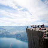 Felsplateau Preikestolen mit Menschen, im Hintergrund Lysefjord, Berge und Himmel