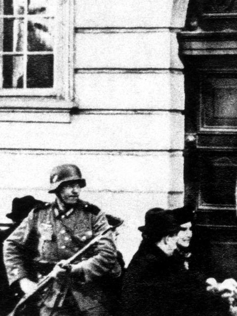 Bewaffnete Uniformierte mit Stahlhelmen vor einer Eingangstür; schwarz-weiß Aufnahme; NS-Zeit