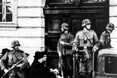 Bewaffnete Uniformierte mit Stahlhelmen vor einer Eingangstür; schwarz-weiß Aufnahme; NS-Zeit