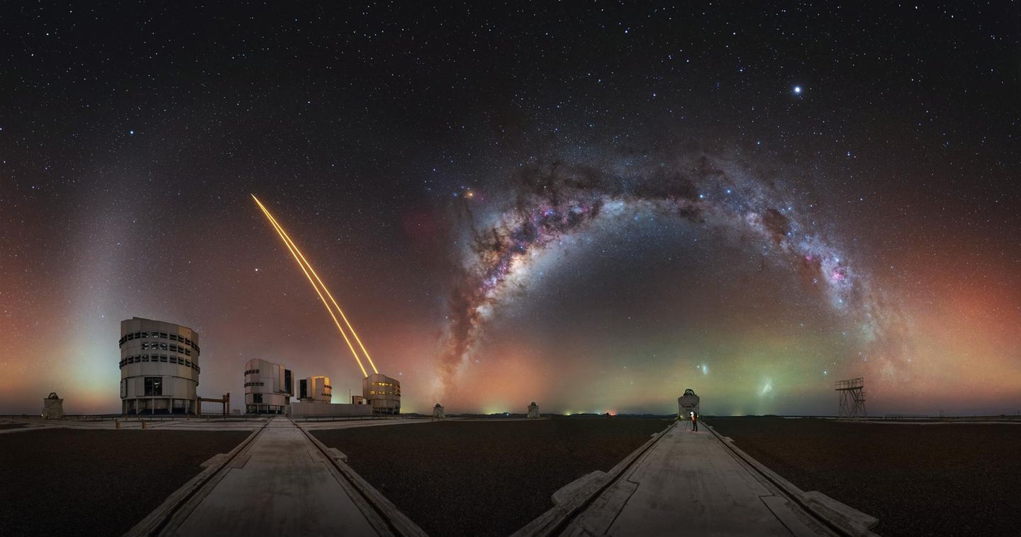 Über der Atacama-Wüste im Norden Chiles. Dem Astrofotografen Julien Looten gelang dieses spektakuläre Kugelpanorama. In dessen Zentrum krümmt sich das Sternenband der Milchstraße oberhalb eines Observatoriums des Very Large Telescope der Europäischen Südsternwarte.   Als leuchteten nicht schon genug Himmelskörper, wirft gleich nebenan ein Riesenteleskop Lasersterne in die Nacht. Wenn Turbulenzen die Atmosphäre durcheinanderwirbeln, flackern die künstlichen Sterne, woraus Forschende ablesen, wie die Atmosphäre das Licht auch der echten Sterne verändert.  In der Dunkelheit der Wüste erstrahlt schwach grün und rot das Luftleuchten: Wenn am Tage UV-Licht der Sonne auf die Atmosphäre einprasselt, leuchtet diese bis in die Nacht hinein nach. Der weiße Pinselstrich am linken Bildrand, das Zodiakallicht, markiert wiederum die planetare Scheibe: jene Ebene, in der die Planeten um die Sonne kreisen und in der Gas und Staub Sonnenlicht streuen.   KW 05