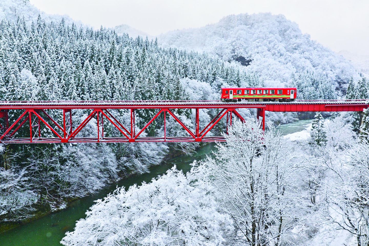 Ein Zug fährt über eine Brücke in einer verschneiten Landschaft