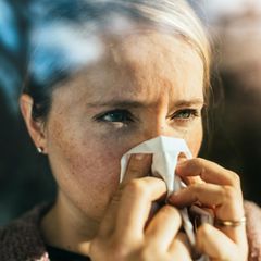 closeup Frau putzt sich die Nase im Sonnenlicht