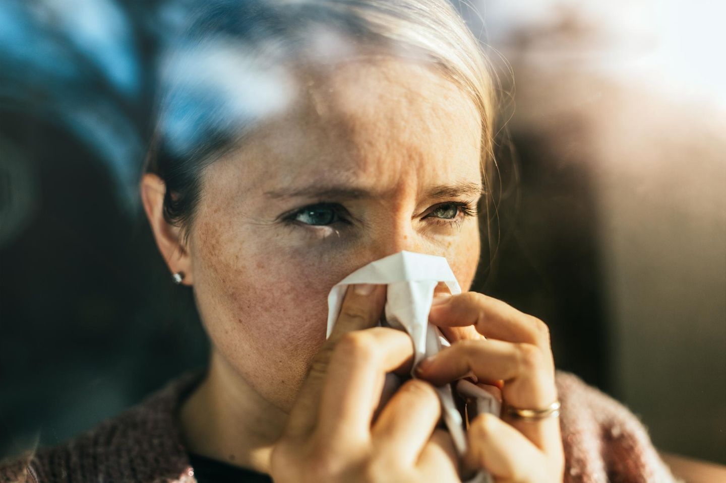 closeup Frau putzt sich die Nase im Sonnenlicht