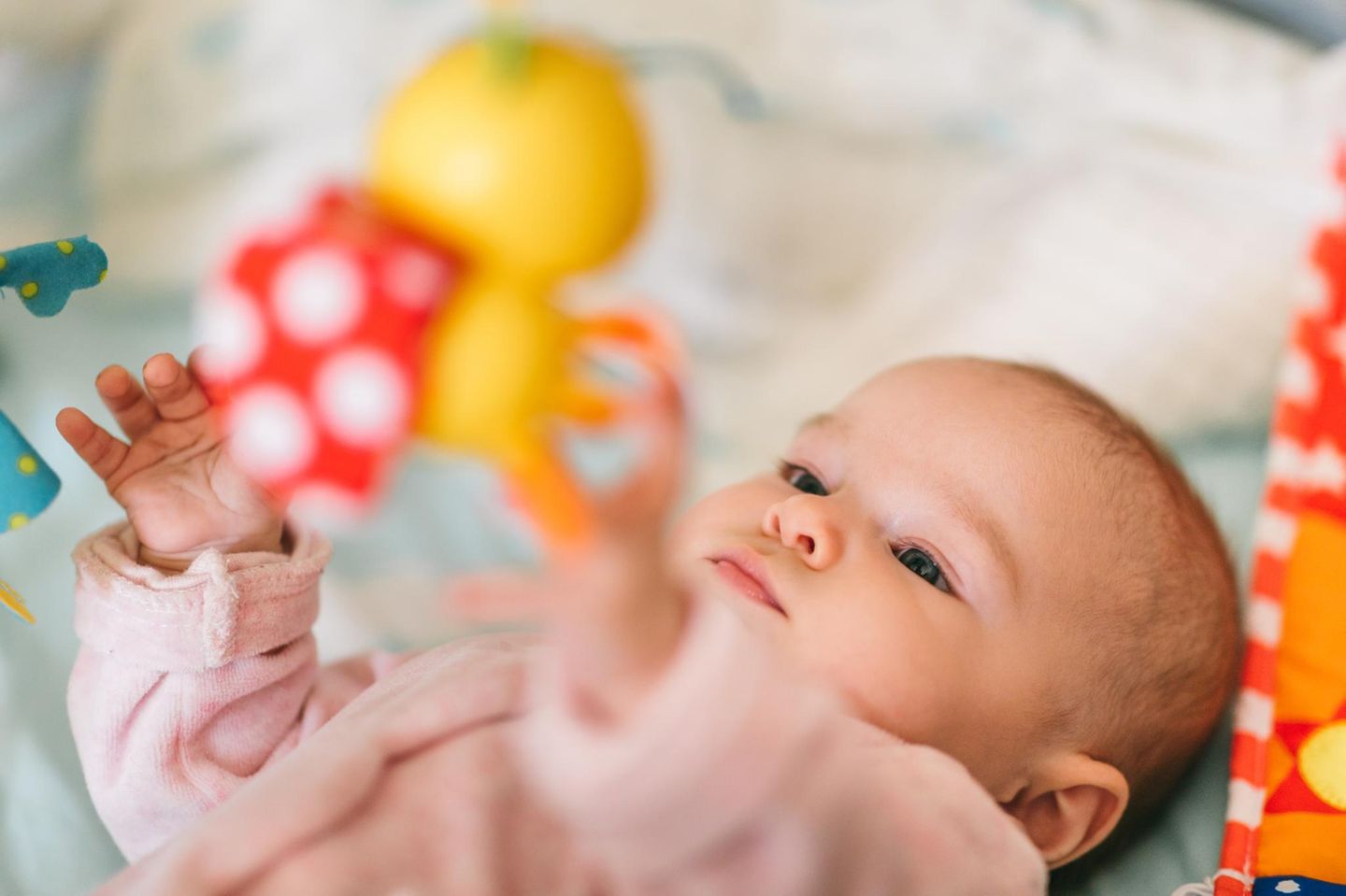 Baby liegt und greift nach Mobile