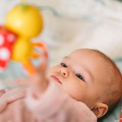 Baby liegt und greift nach Mobile