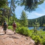 Zwei Wanderer auf einem Uferweg am See
