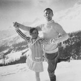 Vor einem Bergpanorama halten sich ein Mann und ein Mädchen  an beiden Händen wie ein Tanzpaar