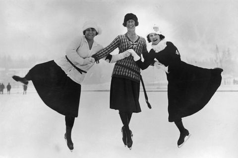 Drei Frauen in Schlittschuhen halten sich über Kreuz an den Händen und springen in die Luft