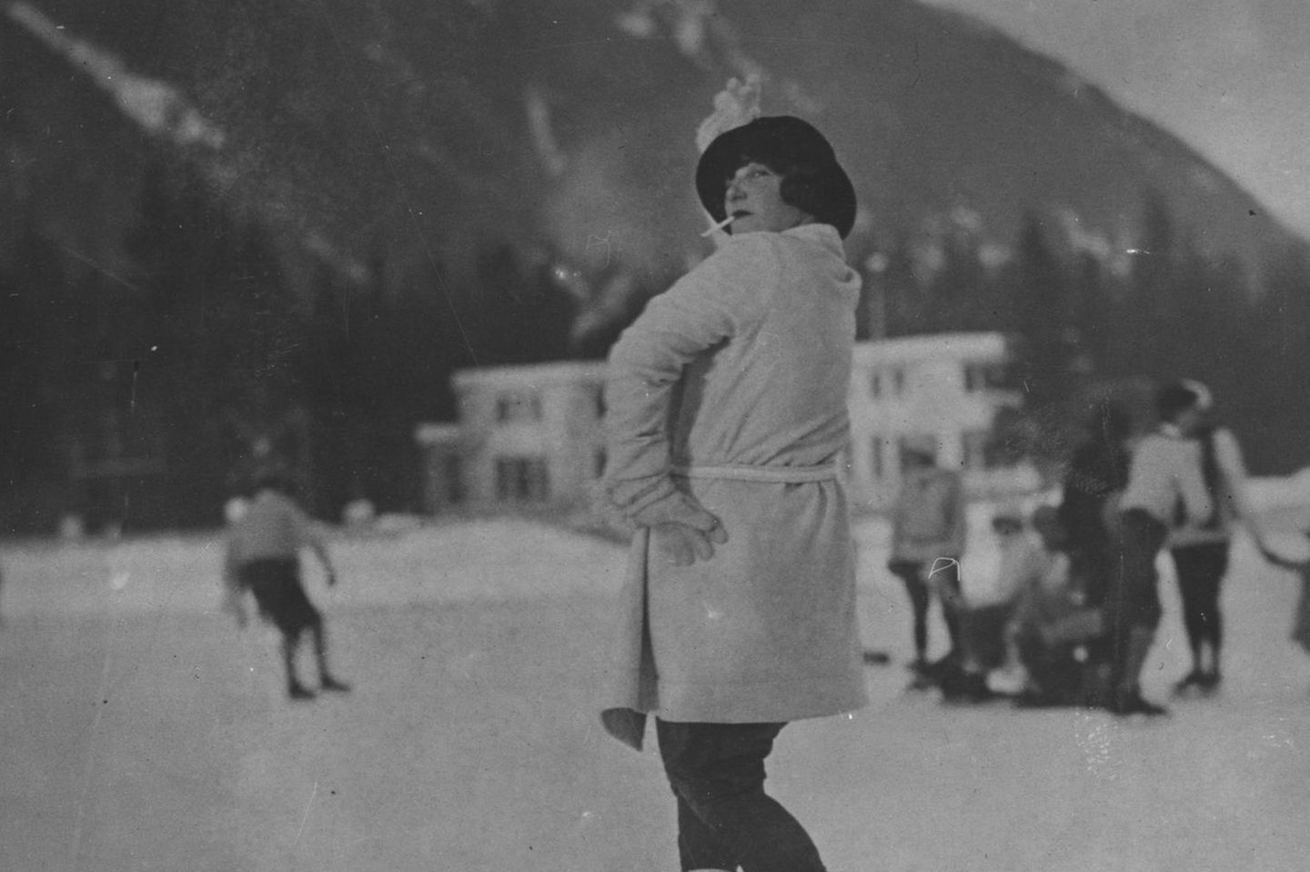 Eine Frau macht auf dem Eis in Chamonix 1924 einen Sprung während sie eine Zigarette raucht