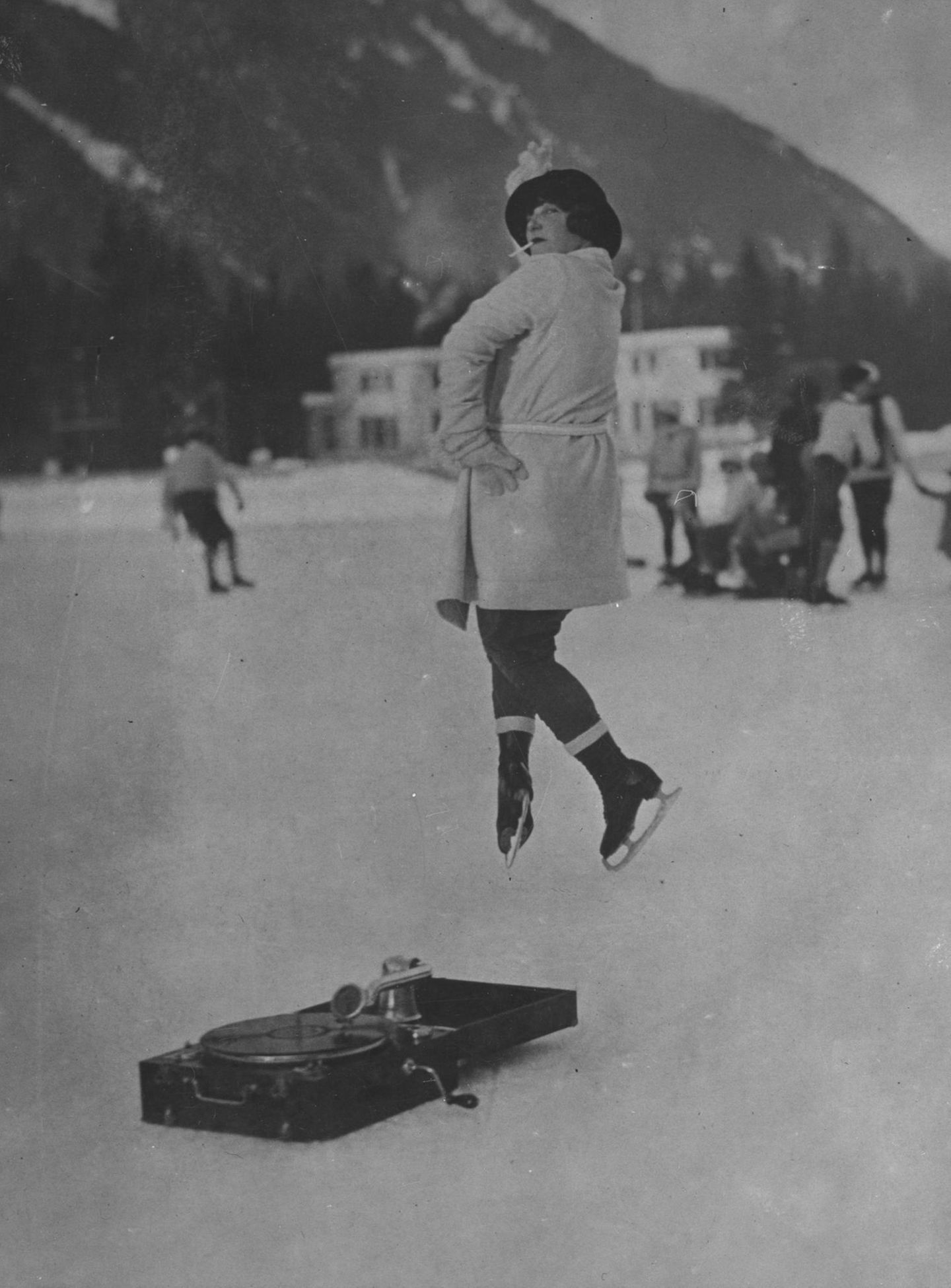 Eine Frau macht auf dem Eis in Chamonix 1924 einen Sprung während sie eine Zigarette raucht