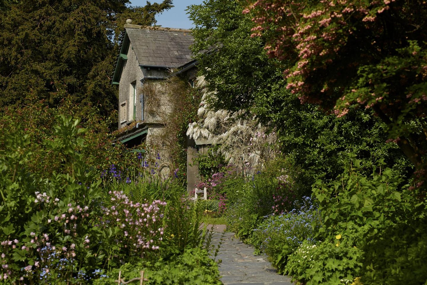 Ein schiefergedecktes Dach und von Blumen gesäumte Wege: Das romantische Bauernhaus Hill Top in England sieht heute noch aus wie zu Lebzeiten der Kinderbuchautorin Beatrix Potter. Hill Top ist in vielen ihrer Werke wiederzuerkennen: Die Figur Bernhard Schnauzbart etwa wohnt in der Wandvertäfelung des Hauses, die Ente Jemima will ihre Eier unter den Rhabarber im Küchengarten legen, und Peter Hase bedient sich am Gemüsebeet von Mr McGregor.